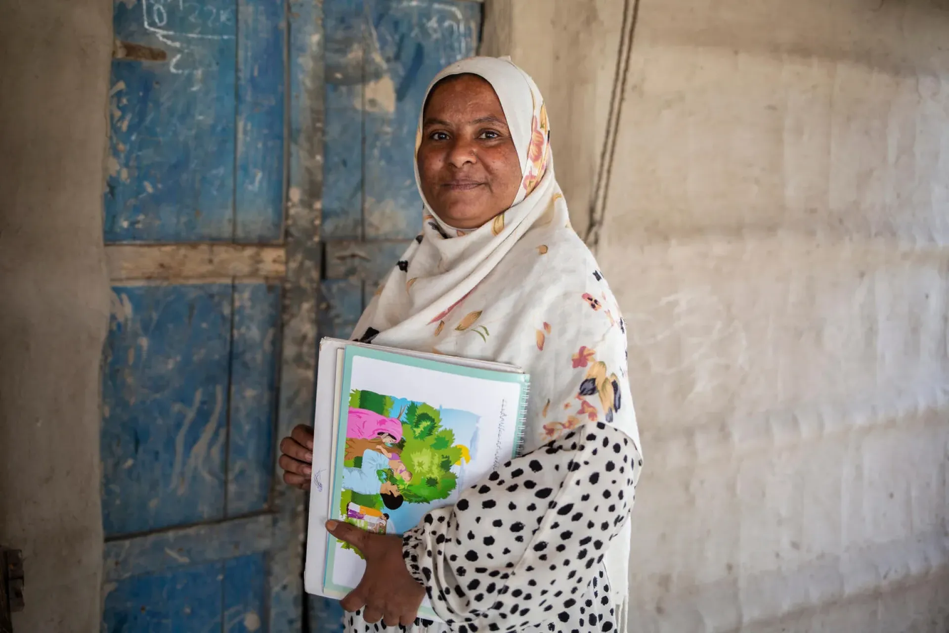 A woman stands holding some picture books.