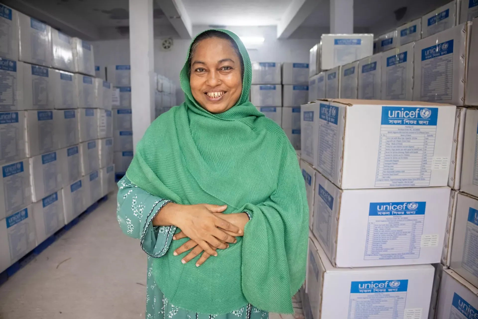 A woman stands in front of emergency supply boxes.
