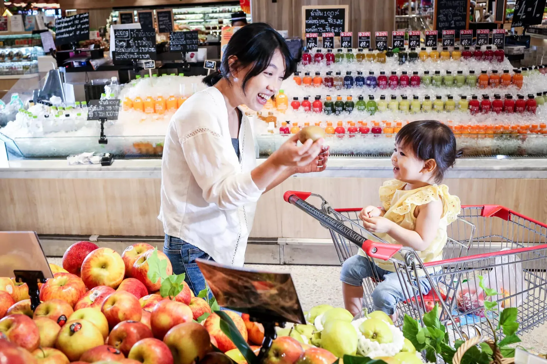 A mother and her child are in supermarket, buying fruits