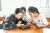 3 adolescent girls sit at a table around a tablet working on a project