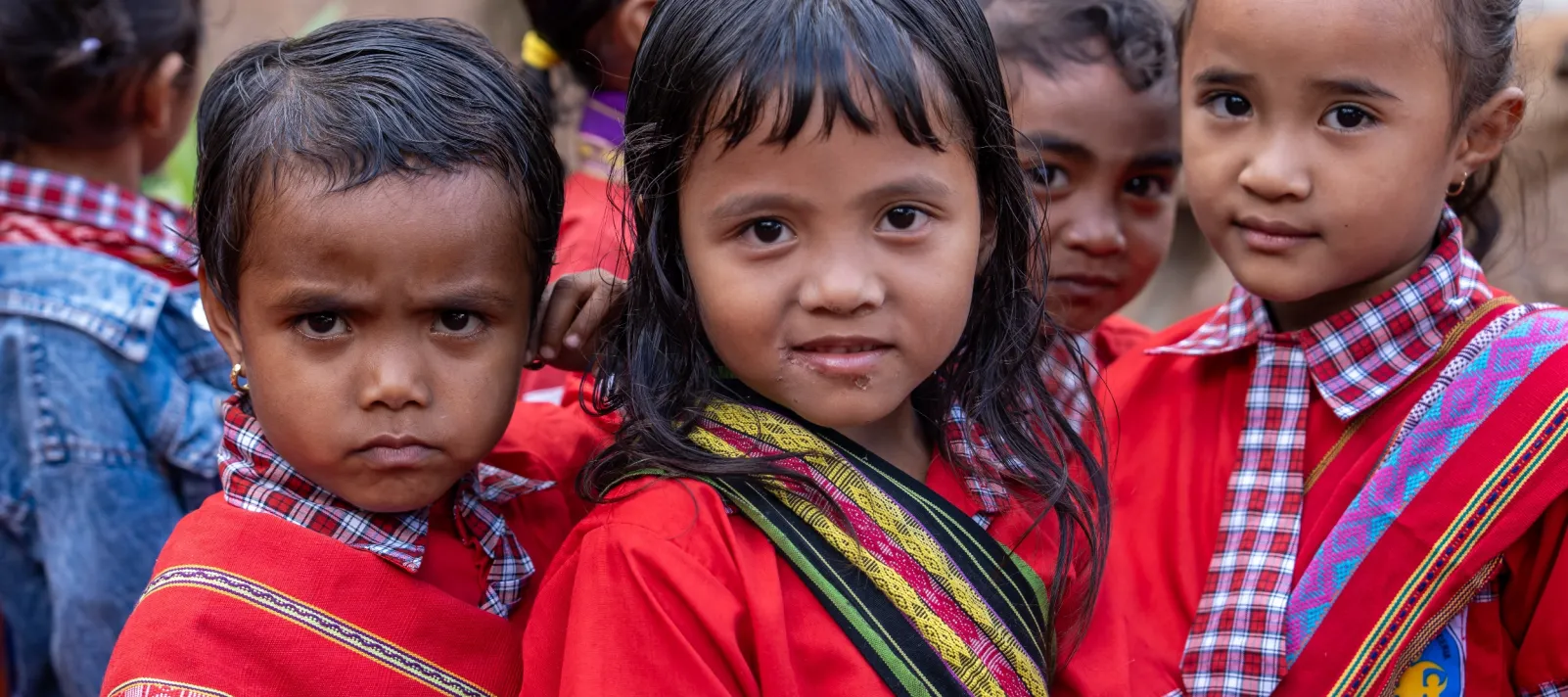 three children in bright red outfits