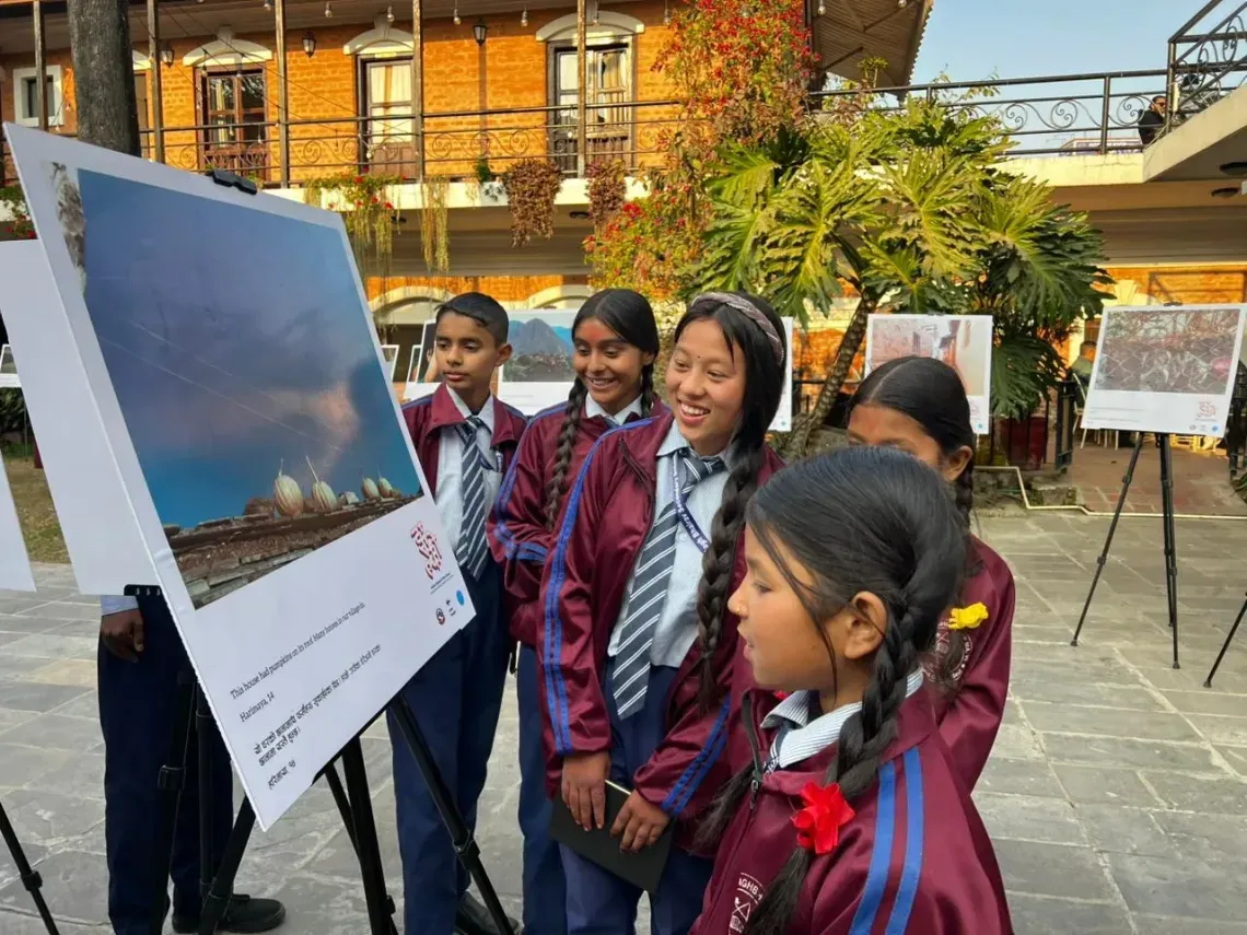 Students smile and look at one of the photos from the exhibition.