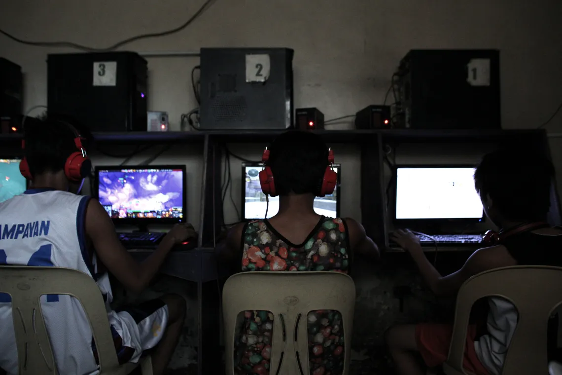 oys of different ages play online video games inside a darkened back room of an Internet caf&eacute; on the outskirts of Metropolitan Manila, Philippines