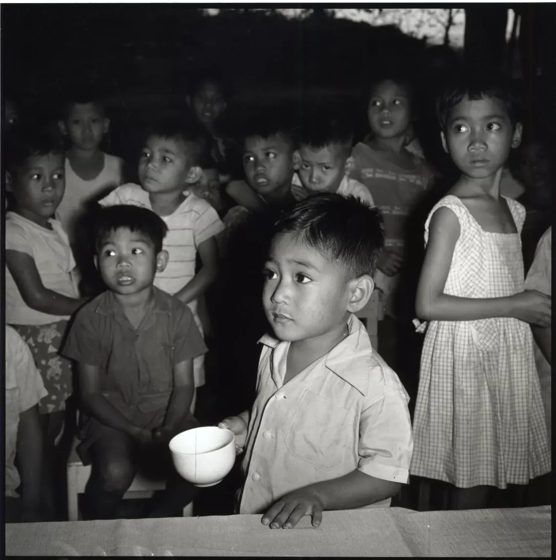 Little Domino, at a child care institution in Philippines, niches his cup of milk while others of his play ,ages are just getting in line for their daily free ration.
