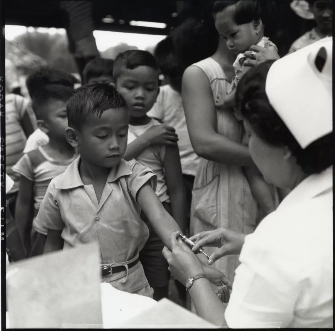 A woman health worker gives a boy an anti-tuberculosis BCG vaccination, while other children and women wait their turn, at a school in Bulacan province.