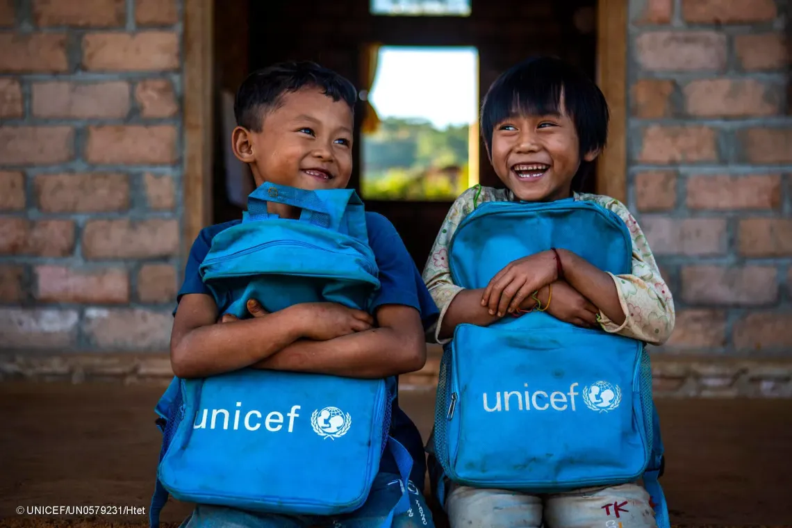 Aung Khin and Kham Li, both 7, hold UNICFE backpacks in front of their classroom at Pan lone hostel, Namtu township, Northern Shan State of Myanmar on 16 December 2021.