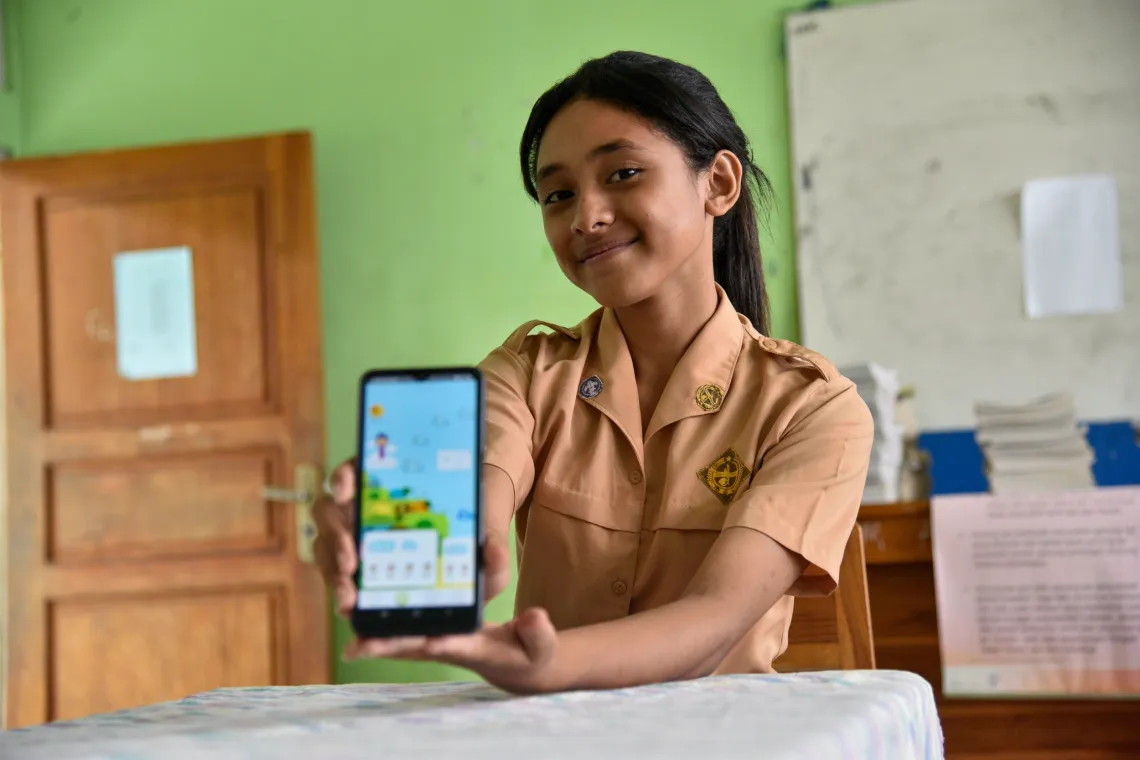 A teenage girl shows the camera an app displayed on her smart phone