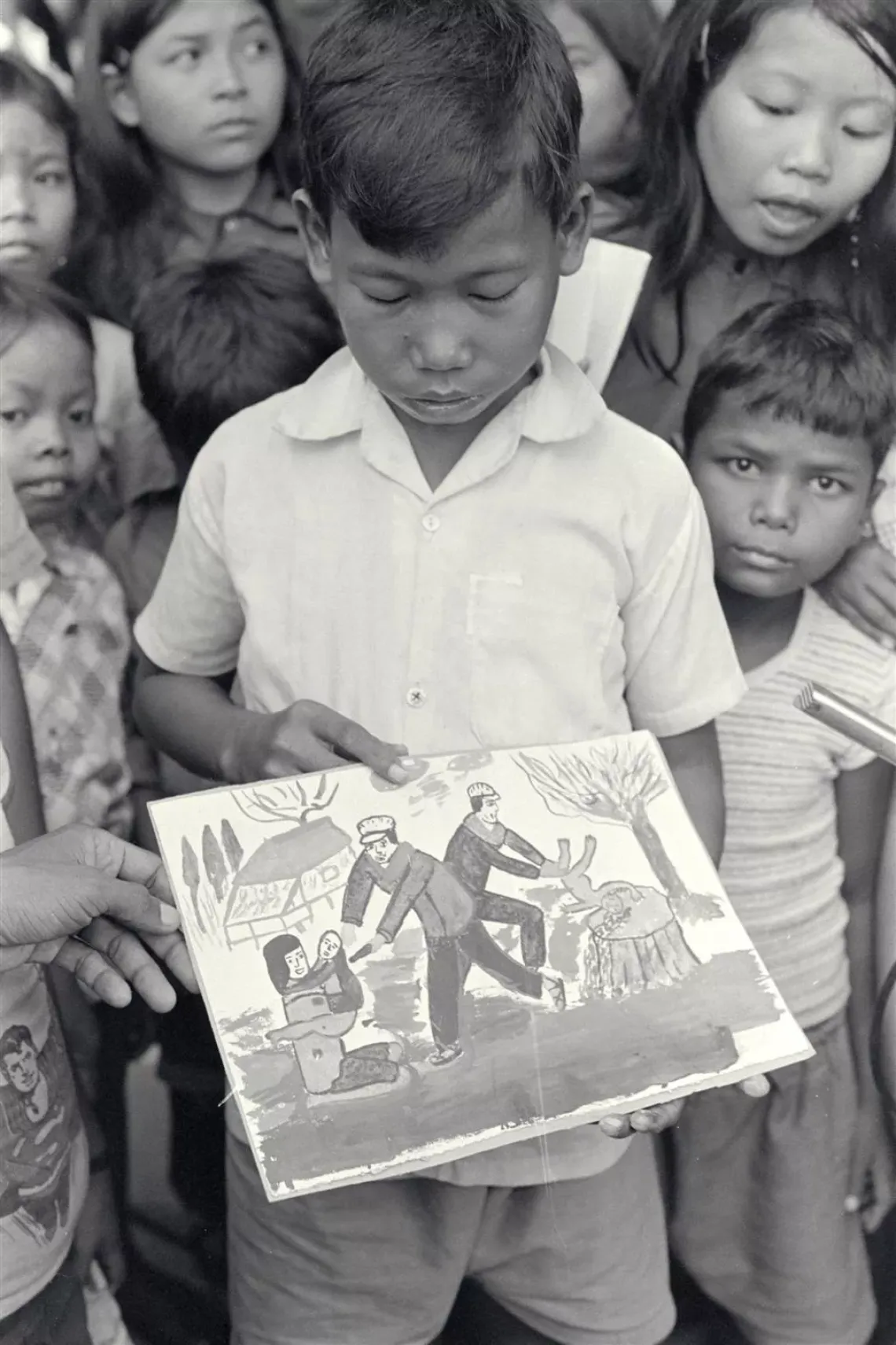 In 1980 in Kampuchea [now Cambodia], a boy in a camp for people displaced by civil conflict shows one of his drawings, which reflects some of the trauma he has experienced. Children who have been uprooted by man-made or natural disasters often bear serious psychological scars.