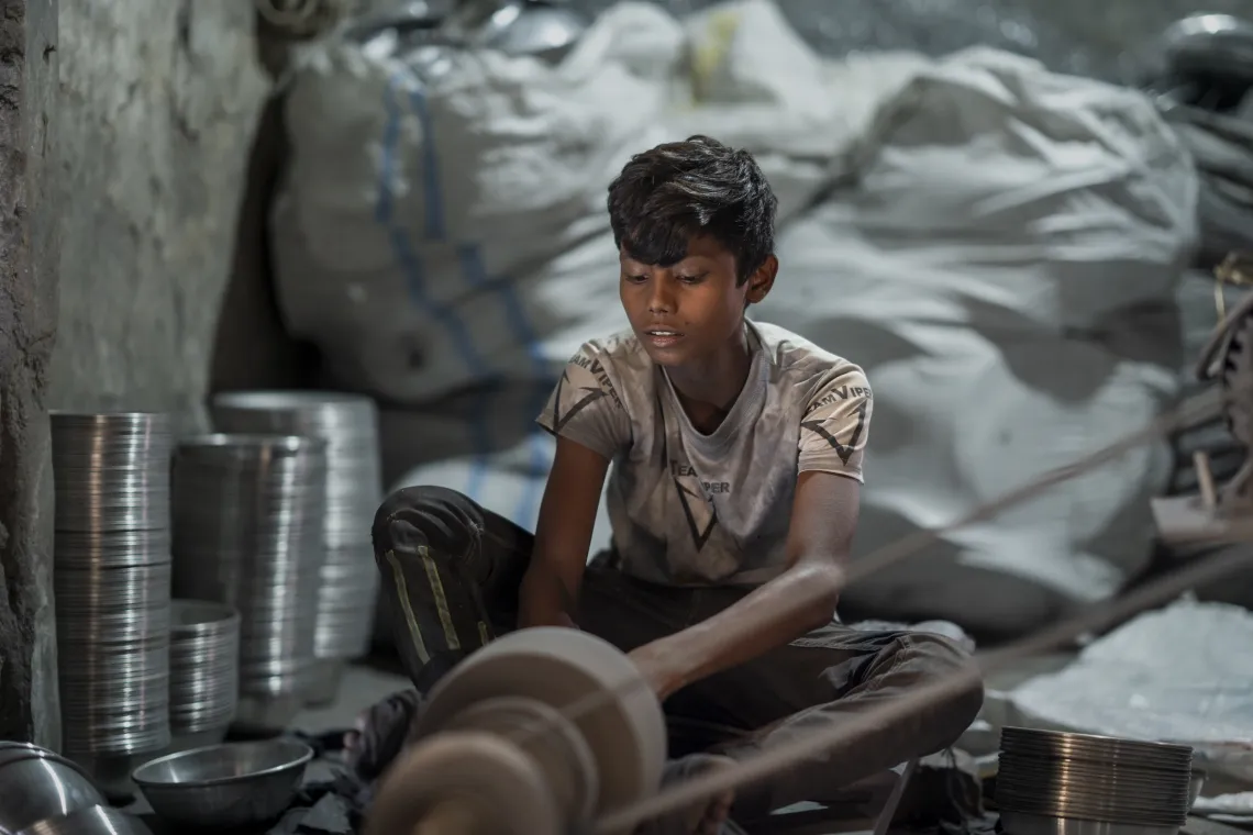 a boy sits while polishing silver