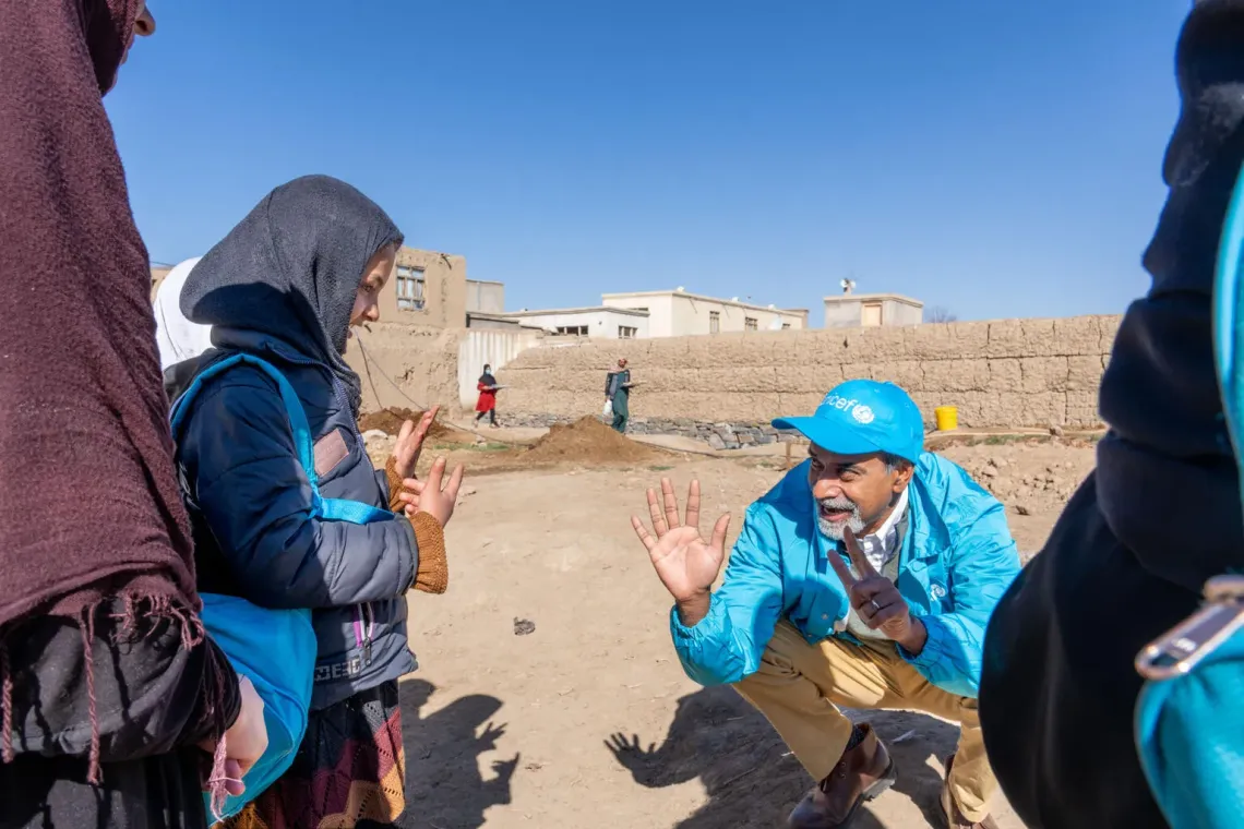 Sanjay interacting with girls inside the premises of a community-based education class. Two students are seen far behind near the premise wall as well.