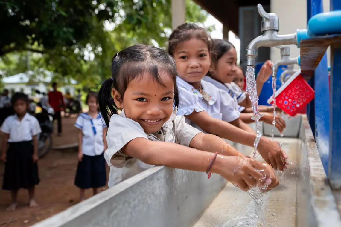 Kim Sovantei (left), 6, and Tin Chantha, 6, wash their hands with other students at the newly installed Water, Sanitation and Hygiene (WASH) station at Sre Chhouk Primary School in Sre Chhouk Village, Rolous Meanchey Commune, Sambo District, Kratie Province, Cambodia. 