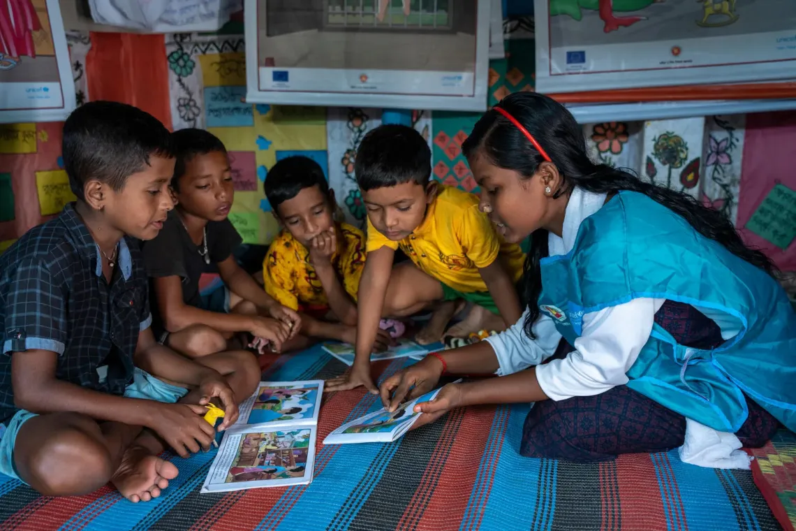17-year-old child protection hub organizer in Shantiganj, is seen teaching paper crafting, drawing, and indoor games to children from the haor area