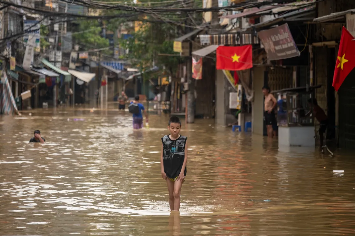 A boy walking in a street flooded after a typhoon in viet nam.
