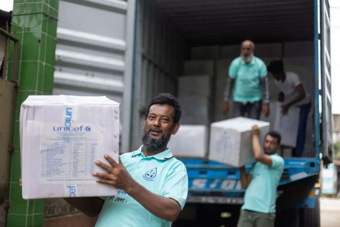 Distributors carries a box with hygiene kits with other distributors handling more in the background.