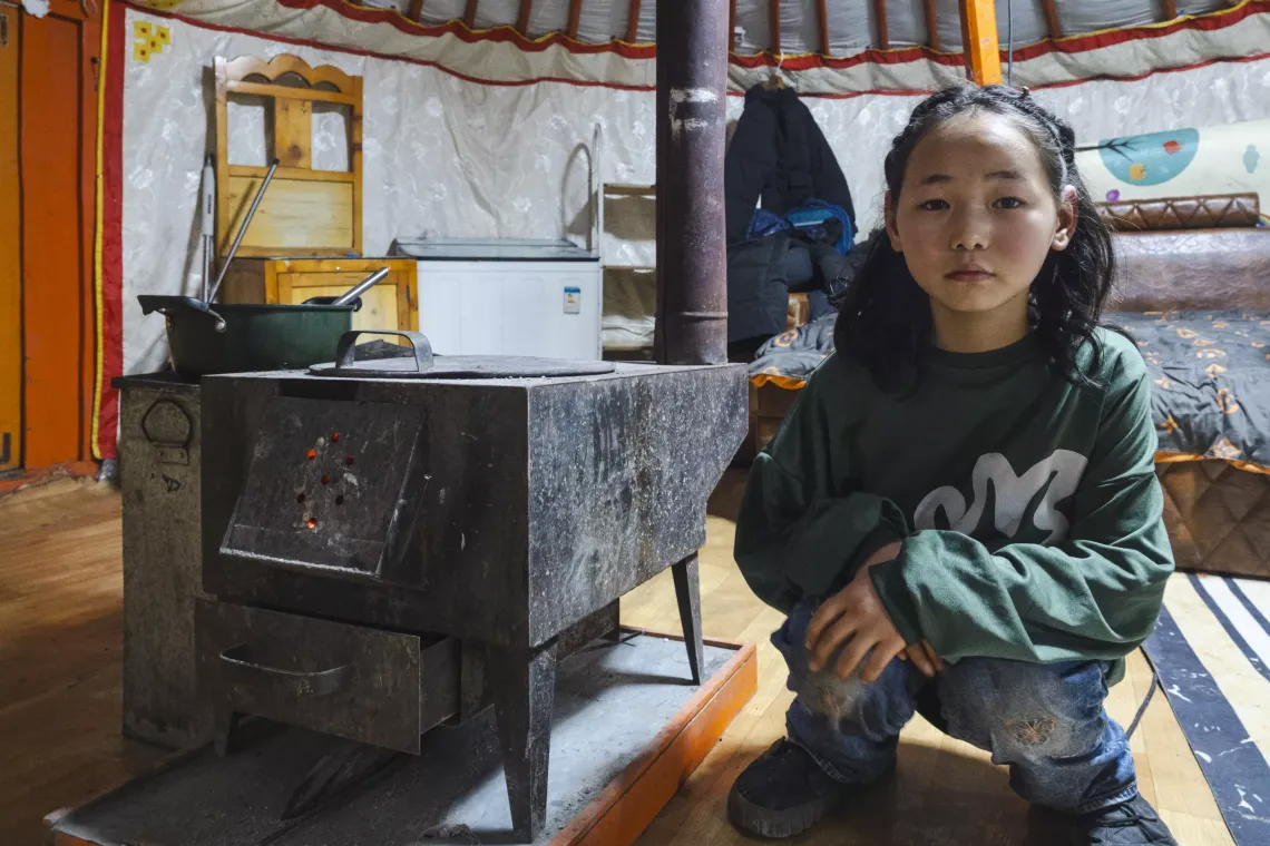 Narangerel, 10, sits near a coal stove in her family ger (traditional Mongolian house) in the Bayanzurkh district of Ulaanbaatar. 