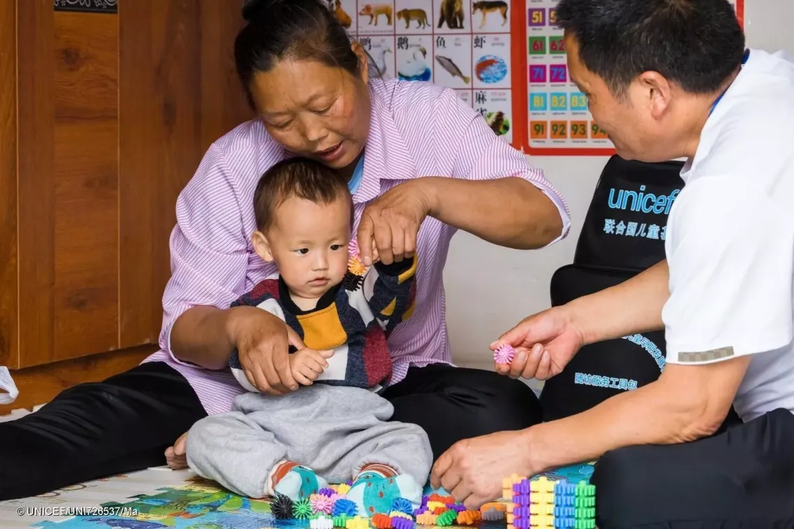  village doctor Zhao Yongsheng visits Li Xiuxiang and her one-and-a-half-year-old grandson, Wenfeng, at their home, teaching Li Xiuxiang how to play with Wenfeng. 