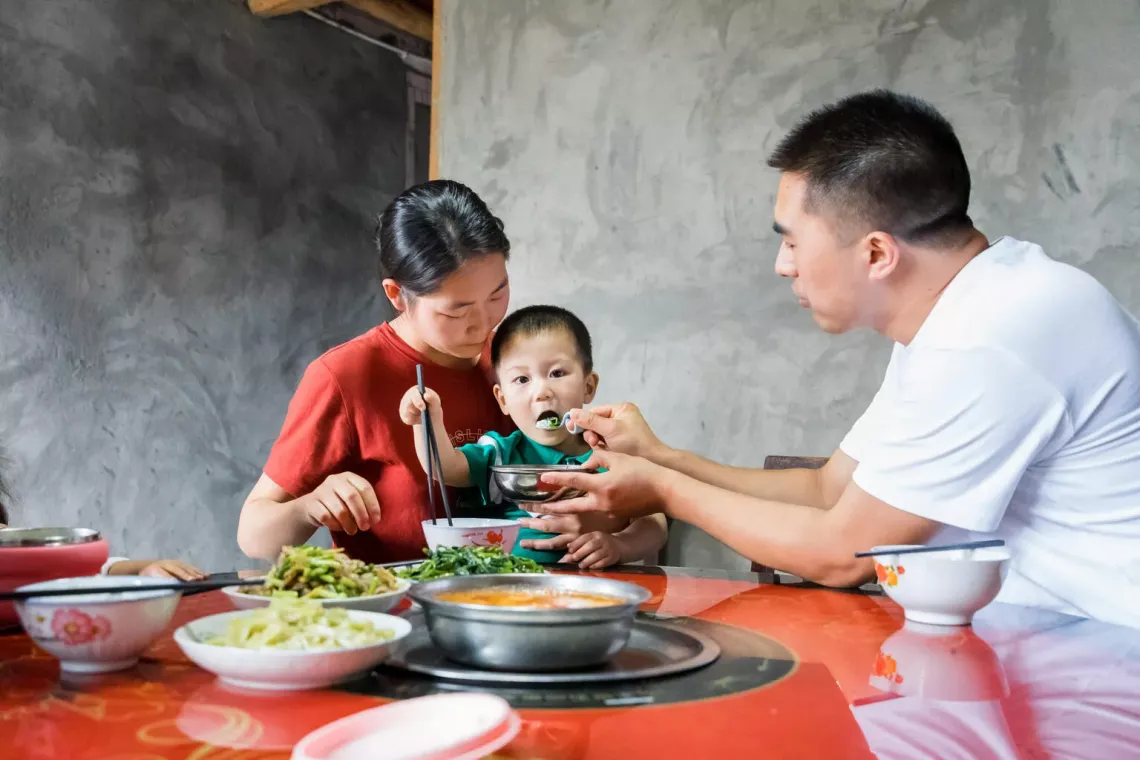  Kaikai's father feeds his two-year-old son, Kaikai, lunch. Kaikai and his parents benefit from the early childhood development (ECD) programme, supported by UNICEF, China