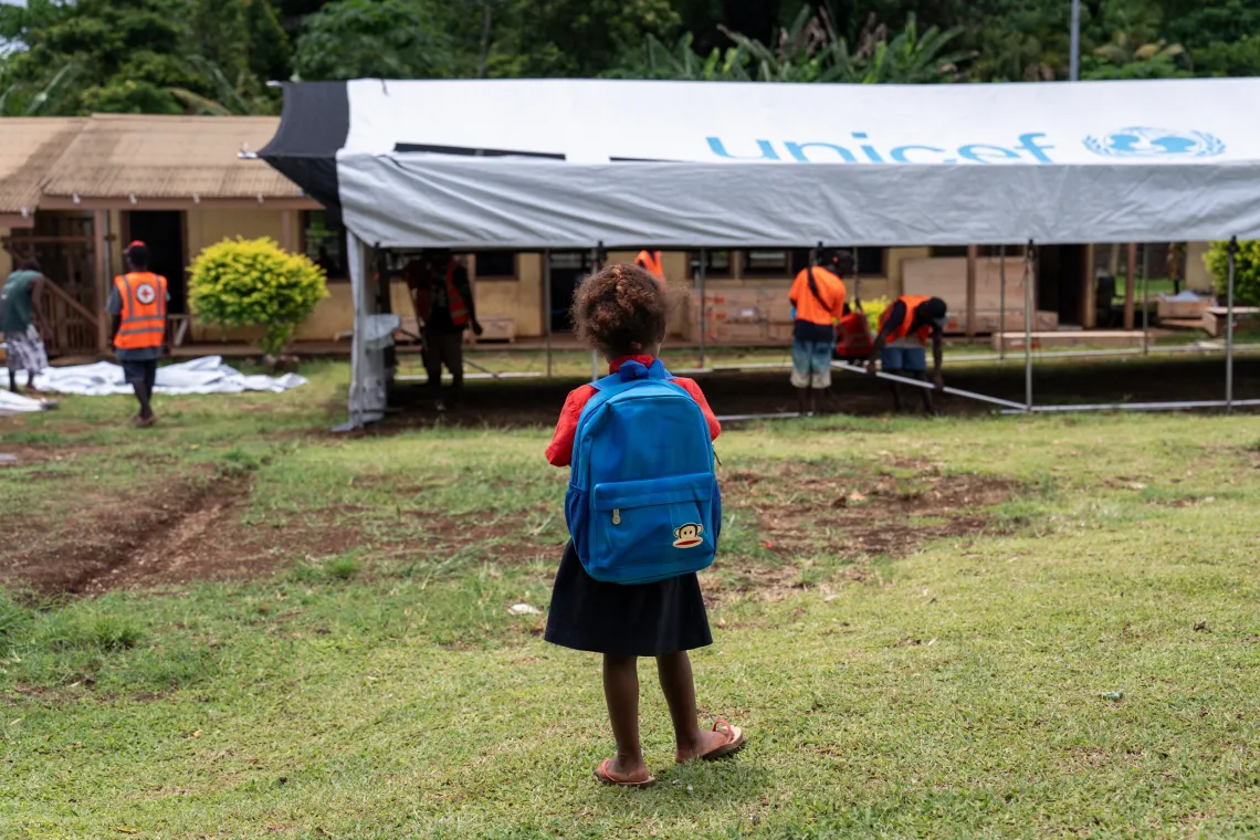 a girl with a backpack looks on as a temp classroom is set up