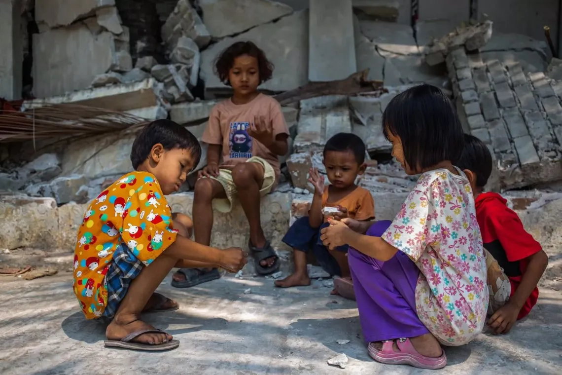 In Myanmar, children play in front of a collapsed wall of the Aye Thukha Community Hall, several days after the devastating earthquake.