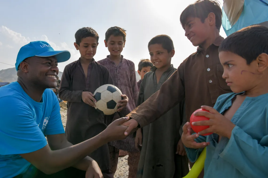 Boys with soccer ball talk to humanitarian worker