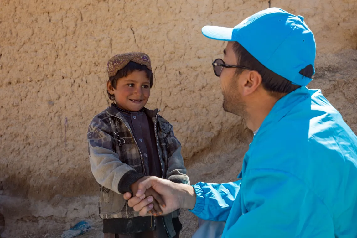 a boy shakes hands with a UNICEF staff person