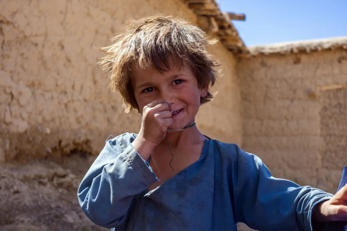 A boy stands outside his home.