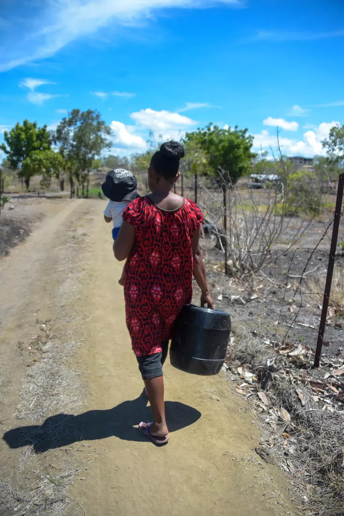 Woman carrying her baby and walking on the road