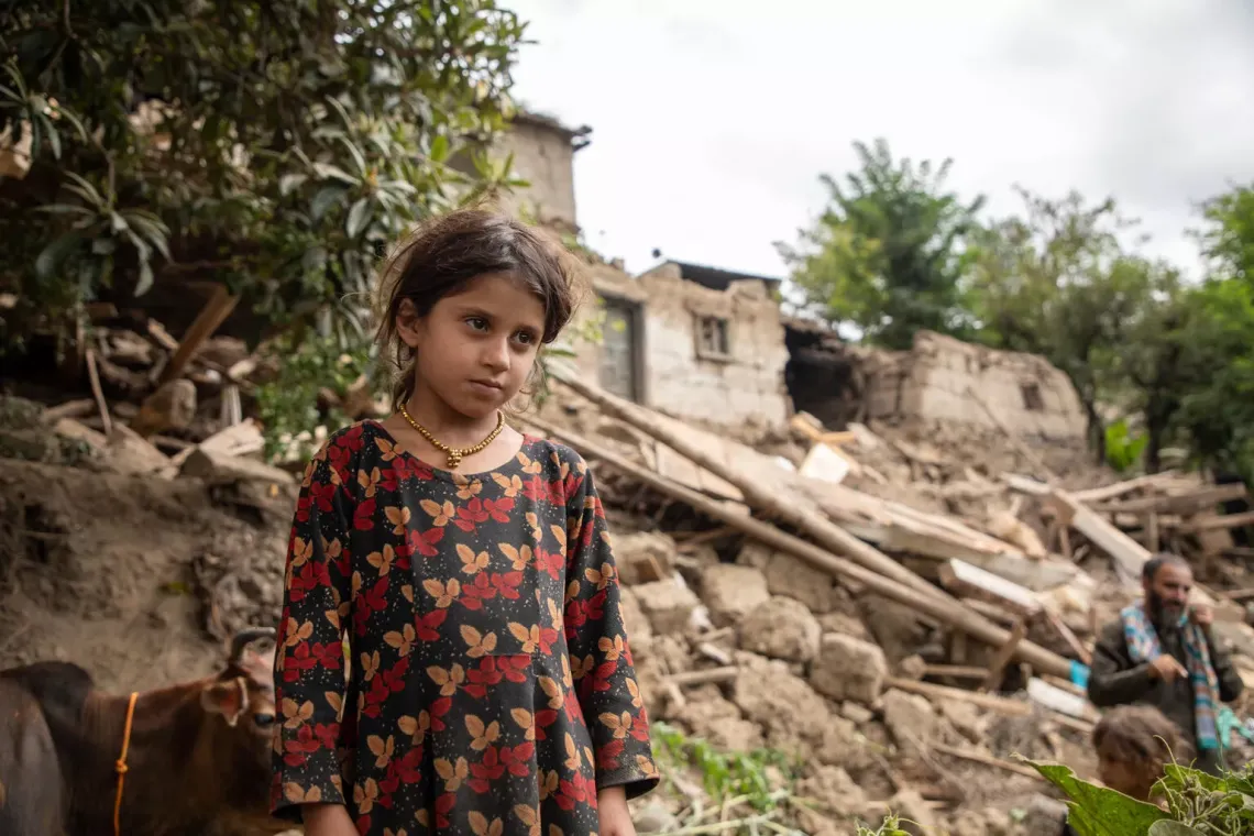 a young girl stands looking out at the destruction after an earthquake