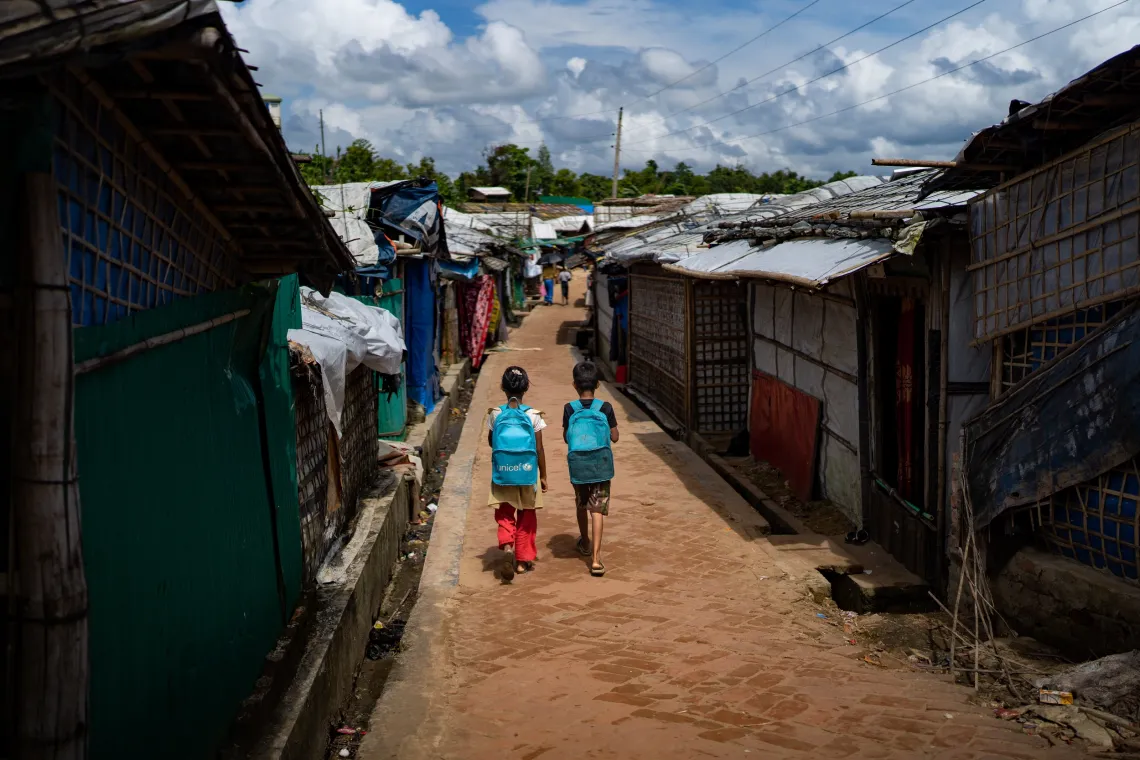 Two children with unicef backpacks walk away from the viewer