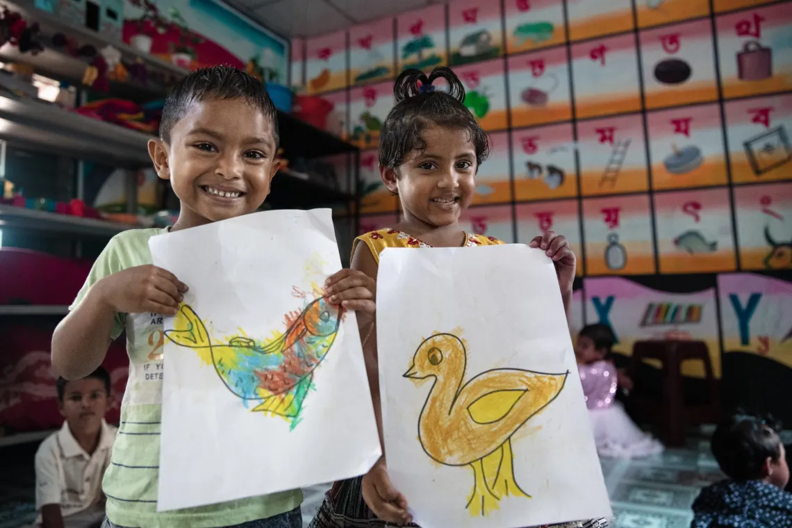 Children proudly display their colorful artwork.