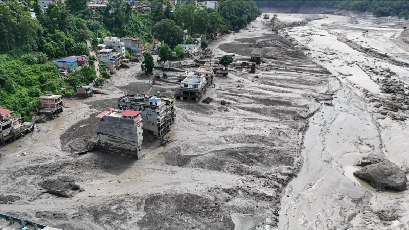Aerial view of severe flooding and mudflow damage affecting homes and surrounding areas.