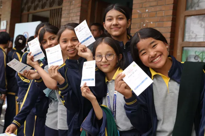 School girls show their HPV vaccine cards.