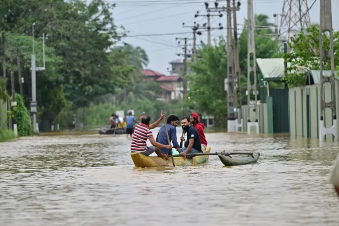 People travel by boat along a flooded street in Ambatale.