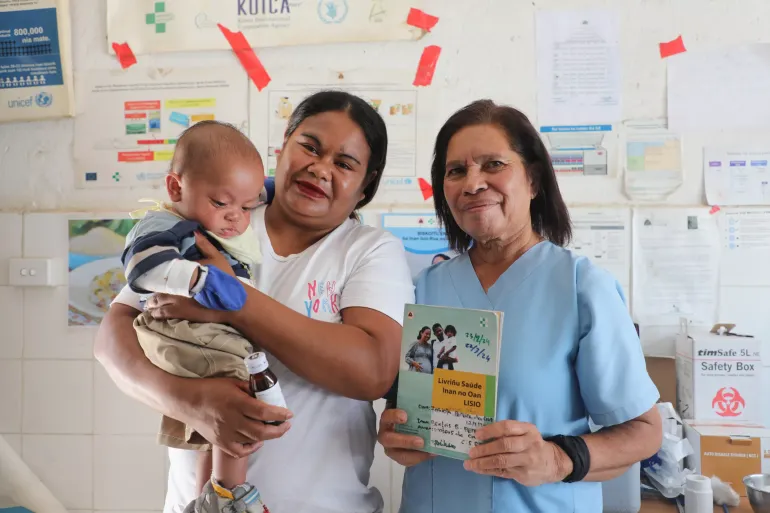 A mother holds her baby girl while standing with a midwife, who is holding a Lisio Book (health check booklet for mother and child), which includes the birth certificate form, April 17, 2024.