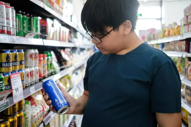 A boy inspects the label of a can of soda in a grocery store near his home in Hanoi