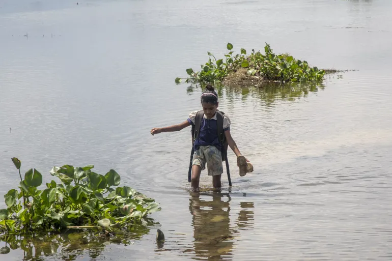 A student from Bangladesh wades through floodwaters in Bangladesh to continue learning