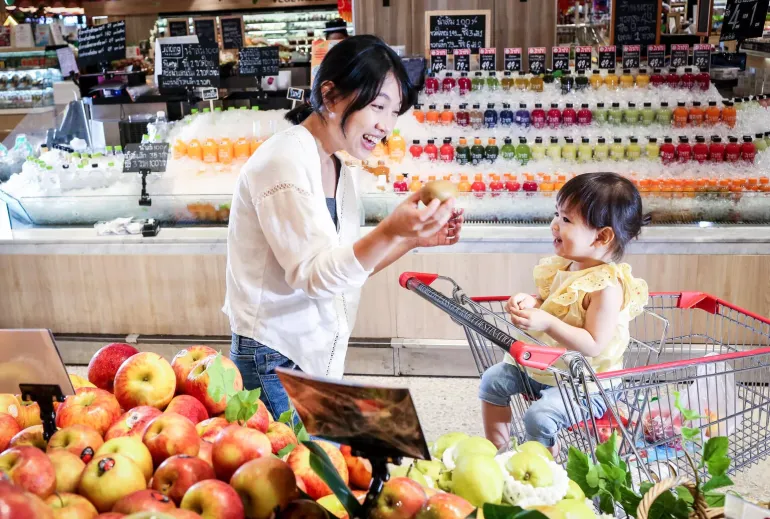 A mother and her child are in supermarket, buying fruits