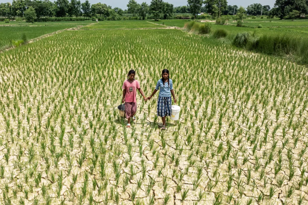 Two girls carrying water buckets for the cracked fields due to lack of rainfall. 
