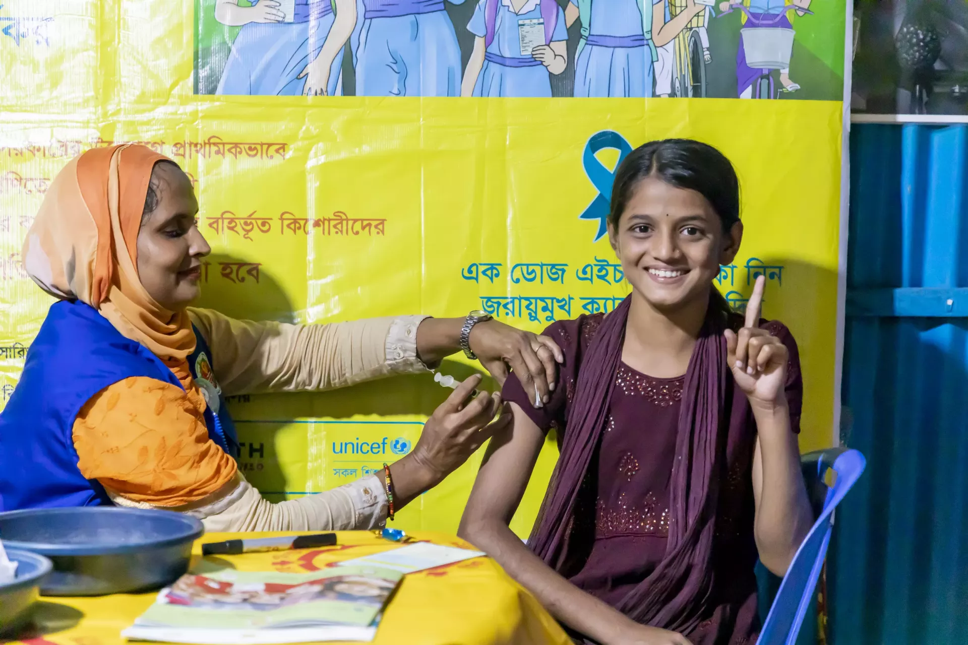 Healthcare worker injecting HPV vaccine to a Bede girl