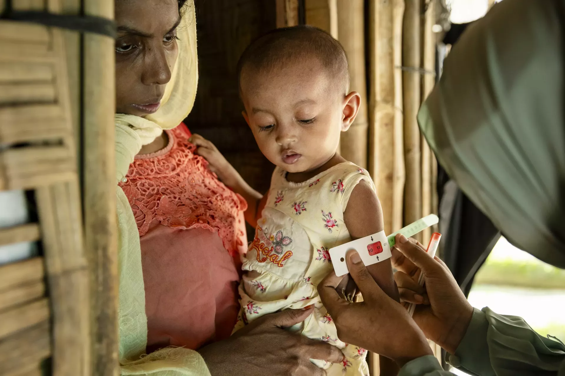 Sofiba, 2, has her mid-upper arm circumference (MUAC) measured by a community nutrition volunteer to assess her nutritional status in the Rohingya refugee camps in Cox&rsquo;s Bazar, Bangladesh.
