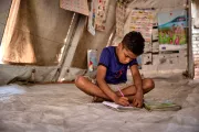 Hasib at a UNICEF Child Protection Service Hub, practising his school work, resting and eating a healthy meal. At the hubs, children also receive counselling, and have the opportunity to play and learn with other children.