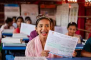 Kosmida, 15, holds up the first year-end assessment card that she has ever received at a UNICEF-supported learning centre in the Rohingya refugee camps in Cox&rsquo;s Bazar, Bangladesh.