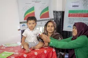 Panna checks baby Aksha&rsquo;s nutrition status by measuring mid-upper arm circumference (shortened for MUAC).