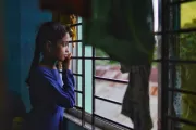 From the window of the school shelter, Smritee looks outside into the roads blanketed with water.