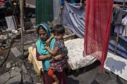 Taslima with her daughter, Mim, standing in front of what used to be her house, now nothing more than a pile of ashes and ruins