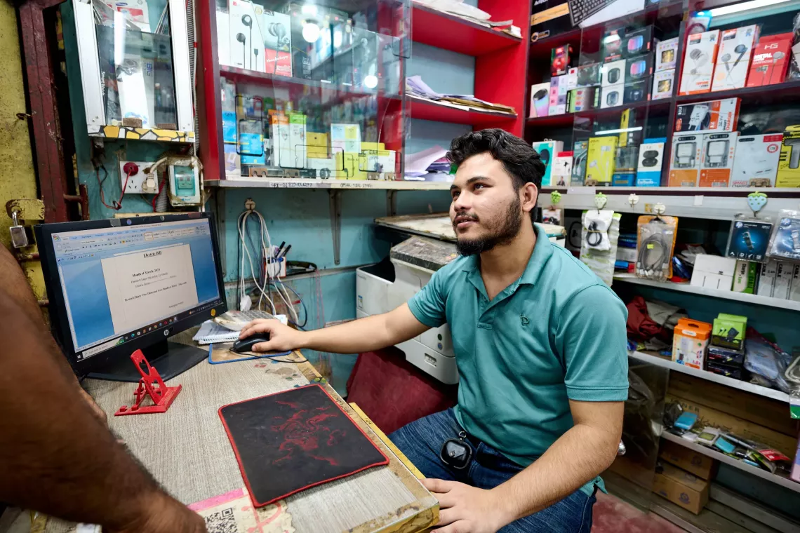 Delwar interacts with a customer at the electronics store.