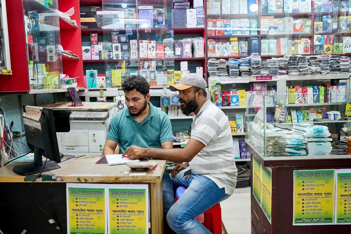 Delwar assists a customer at the electronics store.