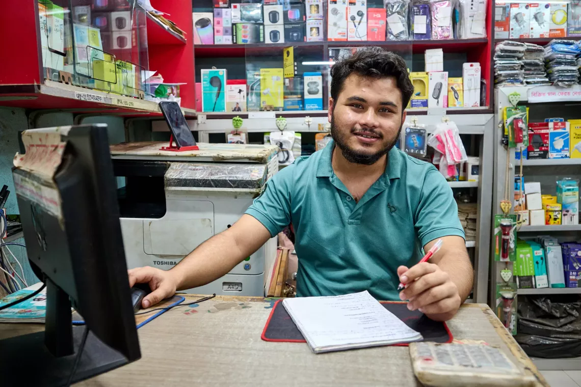 Delwar works on his computer at the electronics store.