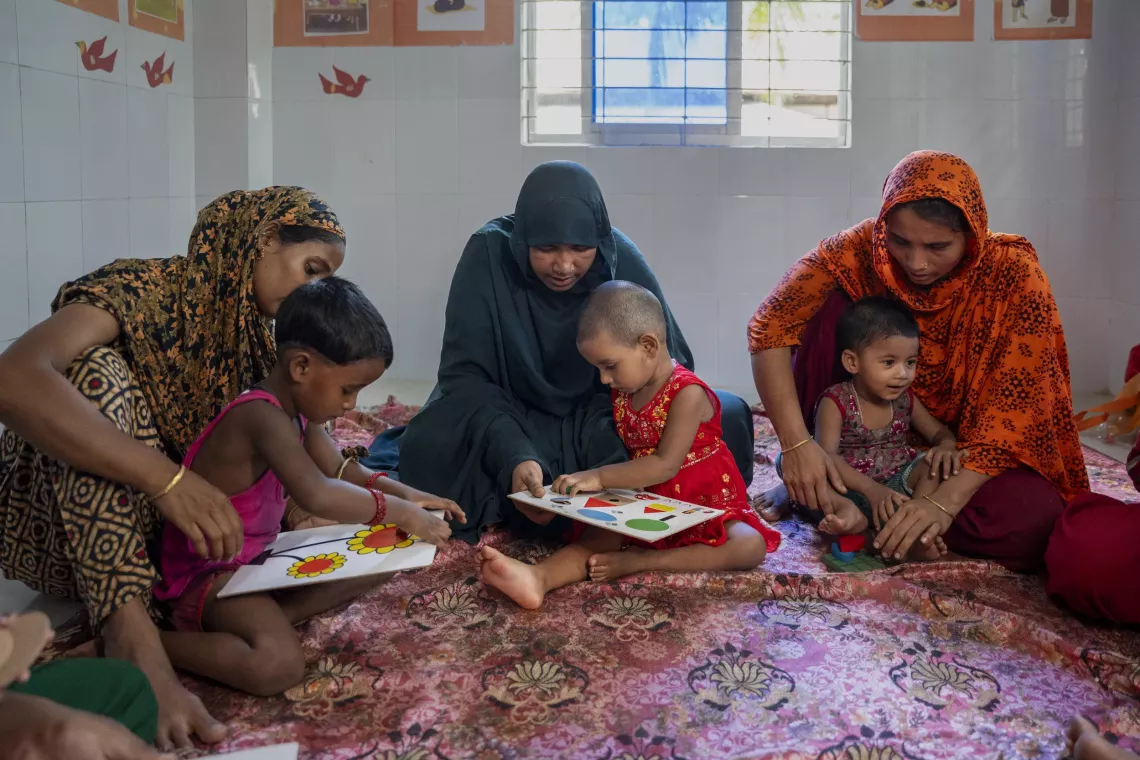 Fahima plays with her 18-month-old daughter Roza (middle) during an ECD session in Bhola. With the guidance of Prodip, she is using picture books and toys to nurture Roza&rsquo;s early stimulation and development. 