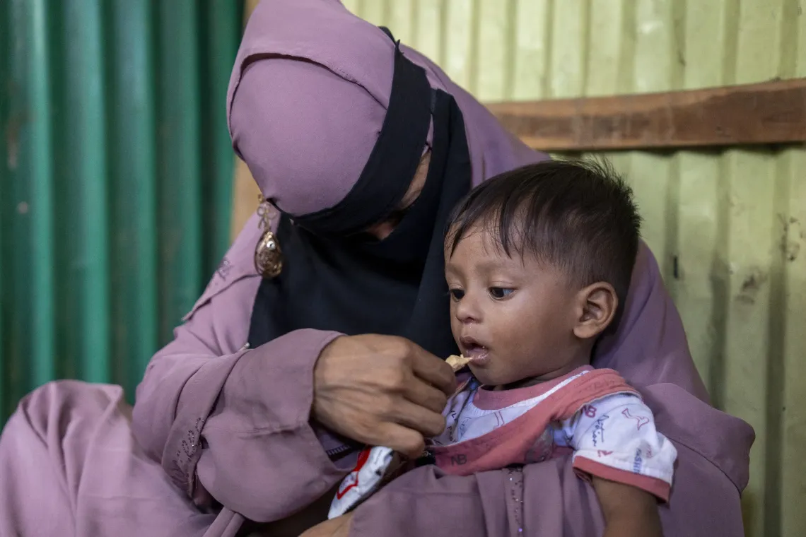 Aziz being fed RUTF by his mother, Nur Kayes (22), as part of an appetite test at the INF.